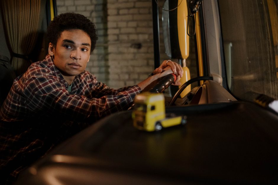 Een vrachtwagenchauffeur aan het werk met een vrachtwagen op de weg, symboliseert carrièremogelijkheden in de transportsector.